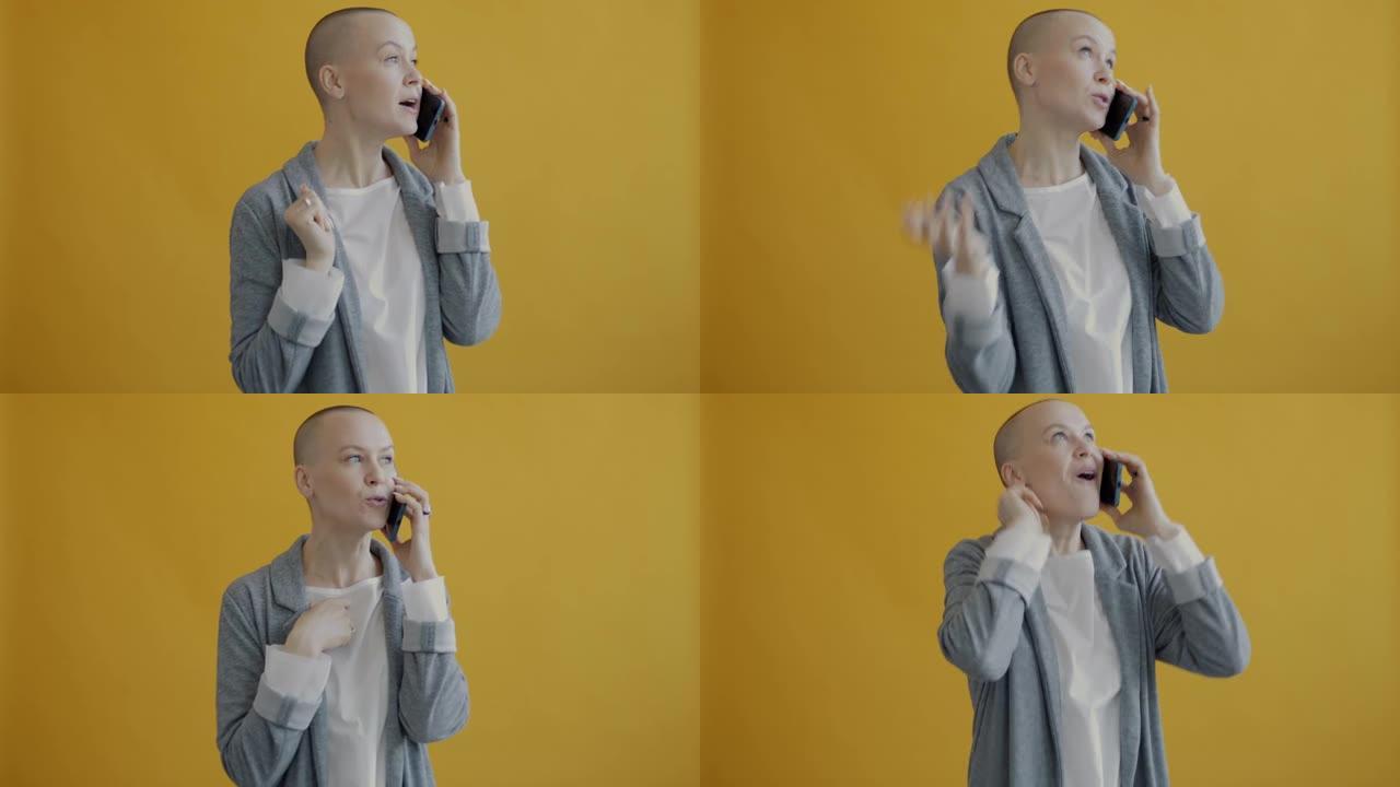 情绪激动的女士在手机上讲话的肖像站在黄色背景上打手势享受通话