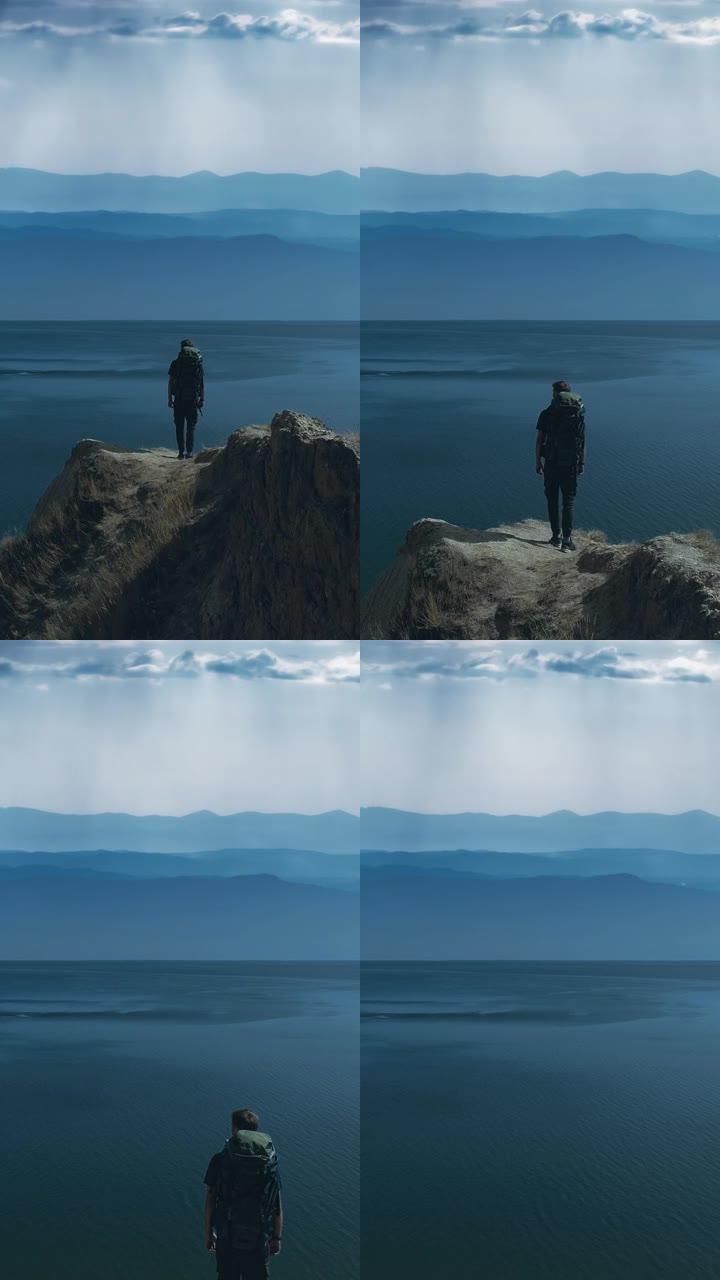 背着背包的男人站在海景背景上的山边