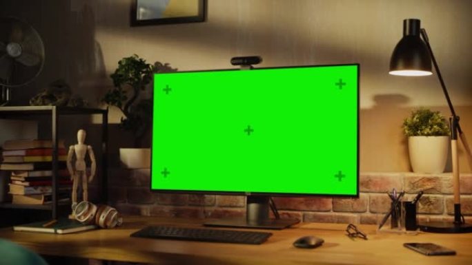 带有绿屏模拟显示器的现代个人电脑显示器站在桌子上，配有键盘、鼠标、智能手机、笔记本电脑和耳机。阁楼客