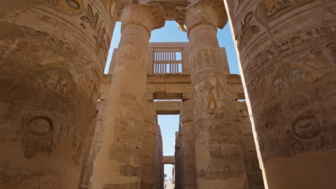 相机在带有古埃及图纸的雄伟圆柱之间移动。万向节高质量镜头。埃及卢克索的卡纳克神庙