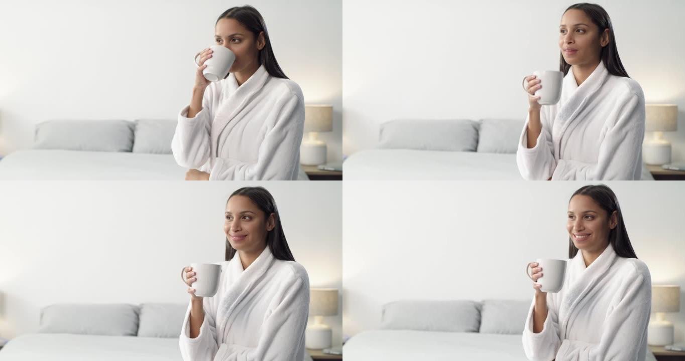 4k视频片段，一名年轻女子早上在家喝咖啡并在床上放松