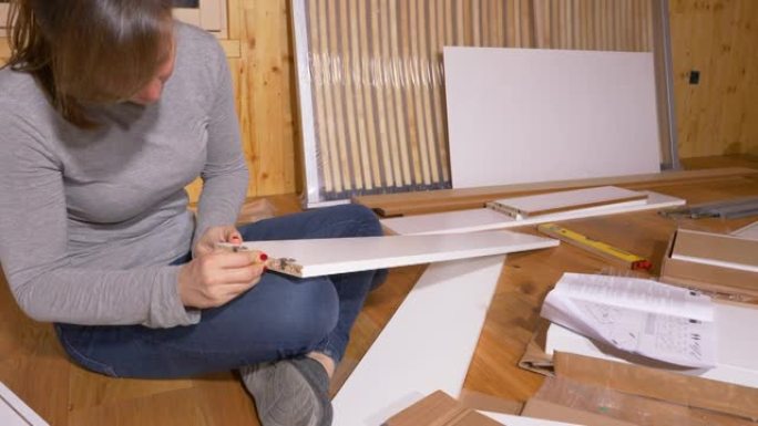 特写: 女性在组装家具时将小木钉粘在木板上。