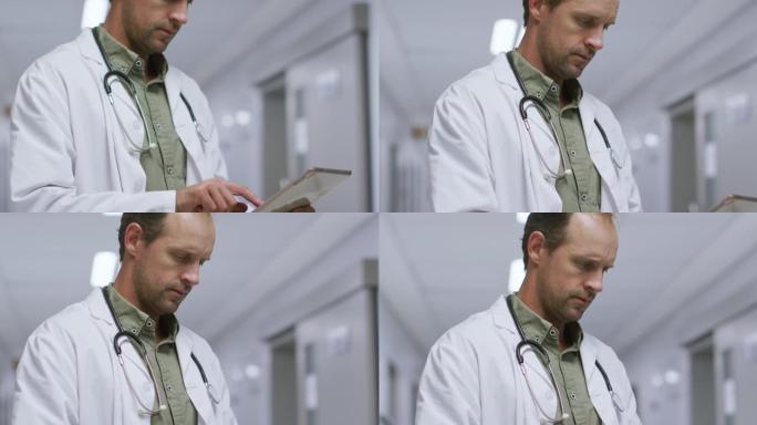 在医院的走廊上使用数字平板电脑的白人男性医生