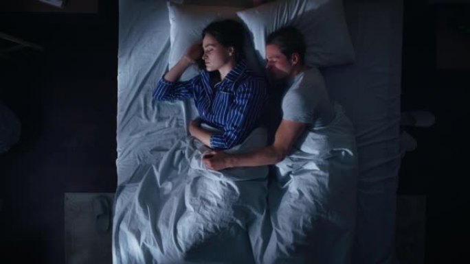 顶景公寓: 幸福的年轻夫妇晚上在床上拥抱在一起睡觉。漂亮的女朋友和帅气的男朋友睡在一起。两口之家甜蜜