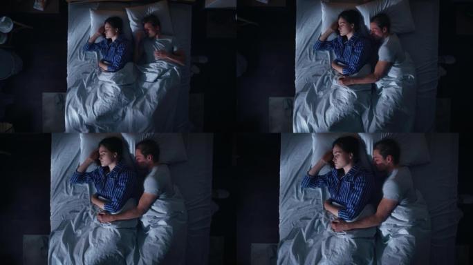 顶景公寓: 幸福的年轻夫妇晚上在床上拥抱在一起睡觉。漂亮的女朋友和帅气的男朋友睡在一起。两口之家甜蜜