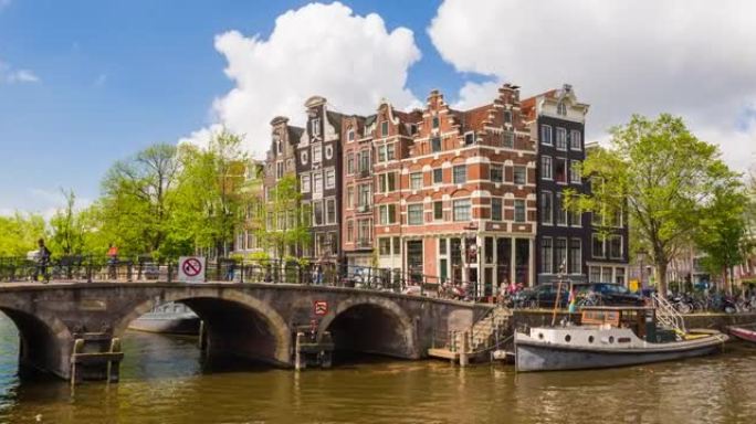 在一个美丽的阳光明媚的日子里，荷兰阿姆斯特丹有船只和倾斜房屋的运河景观