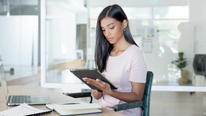 年轻的女实习生在现代办公室的平板电脑上看着，打字和检查社交媒体。员工坐在办公桌前浏览Facebook
