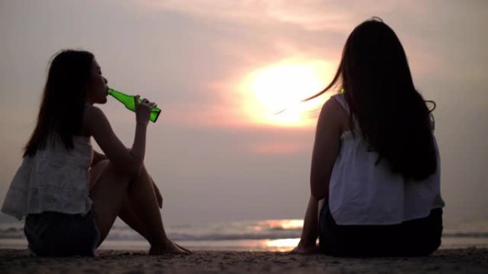 日落时间两名妇女在海滩上喝酒放松