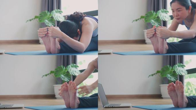 亚洲女子在家用笔记本电脑练习瑜伽