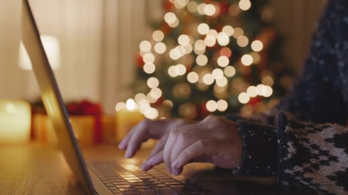 在舒适的家中，在笔记本电脑电子贺卡上打字圣诞快乐。