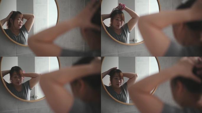 亚洲中国身体积极的女人扎着头发准备在家锻炼，享受周末在家对着镜子化妆