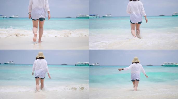 在泰国西米兰岛，蓝色的海和白色的沙滩上享受快乐的女人