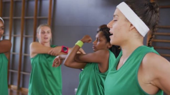 多元化的女子篮球队与男教练拿着剪贴板伸展