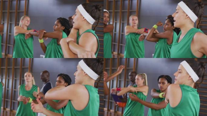 多元化的女子篮球队与男教练拿着剪贴板伸展