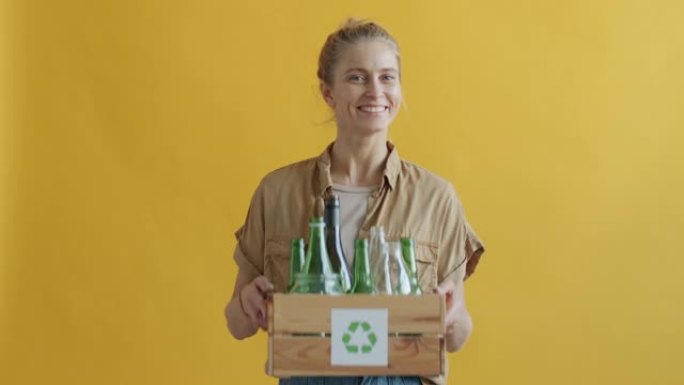 生态活动家的肖像拿着一盒带有回收符号的玻璃瓶