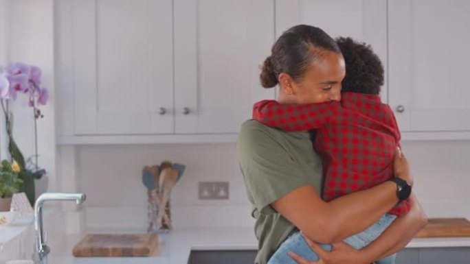 慈爱的母亲在家庭厨房里背着和拥抱儿子-慢动作拍摄