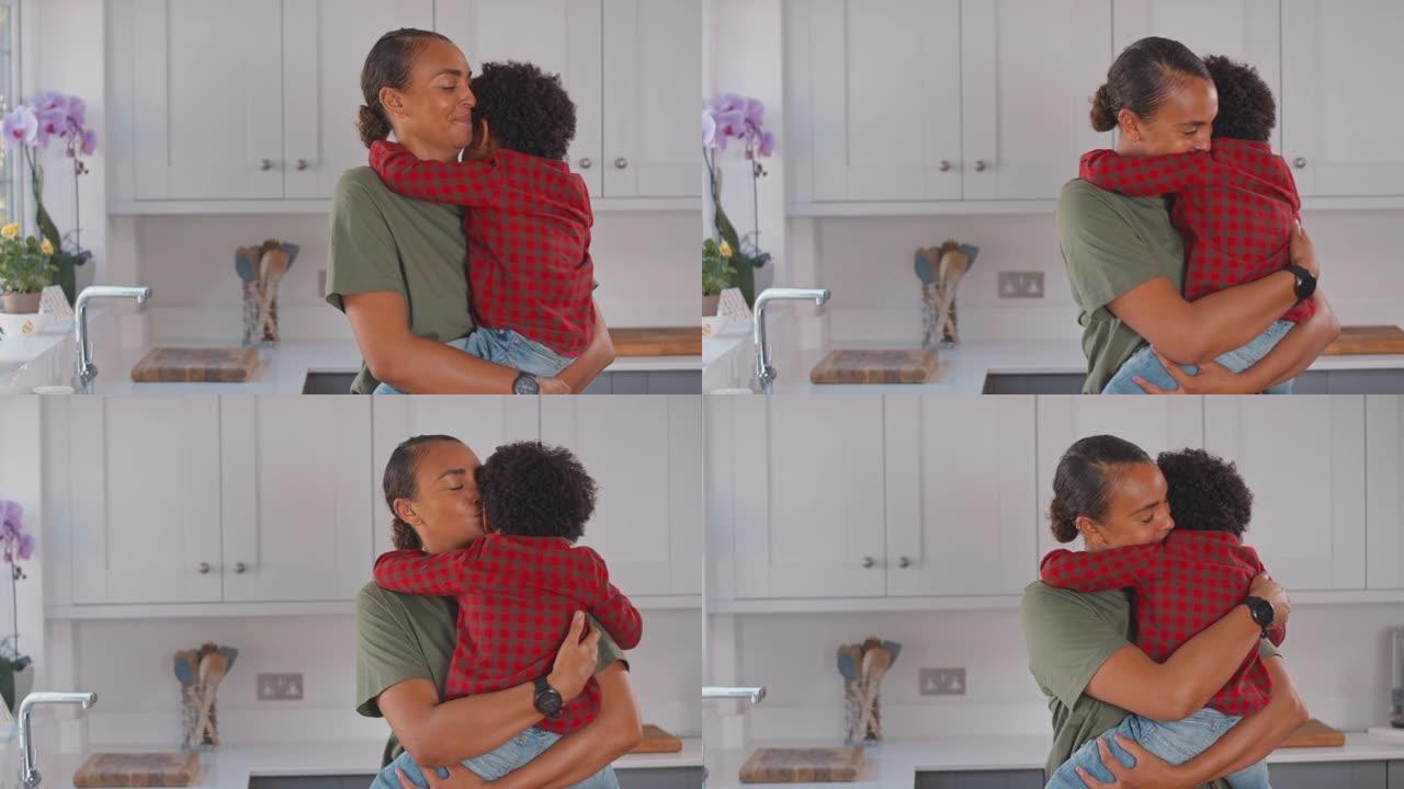 慈爱的母亲在家庭厨房里背着和拥抱儿子-慢动作拍摄