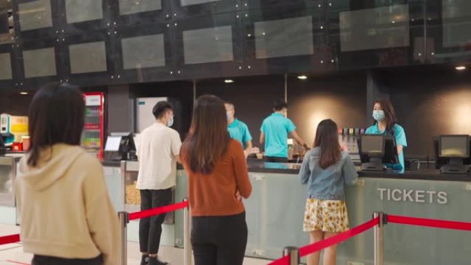 社交距离后视图亚洲华人人群排队等候在电影院购买电影票和小吃新常态练习SOP