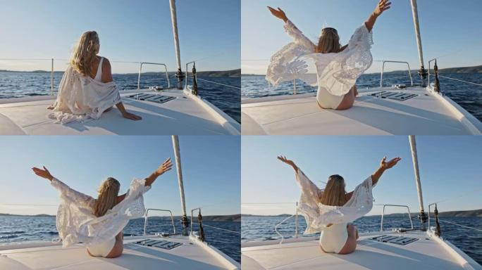 WS年轻女子在帆船甲板上享受微风时举起双手