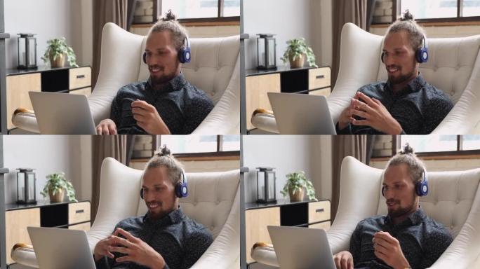 男子坐在扶手椅上使用笔记本电脑应用视频会议进行远程通信