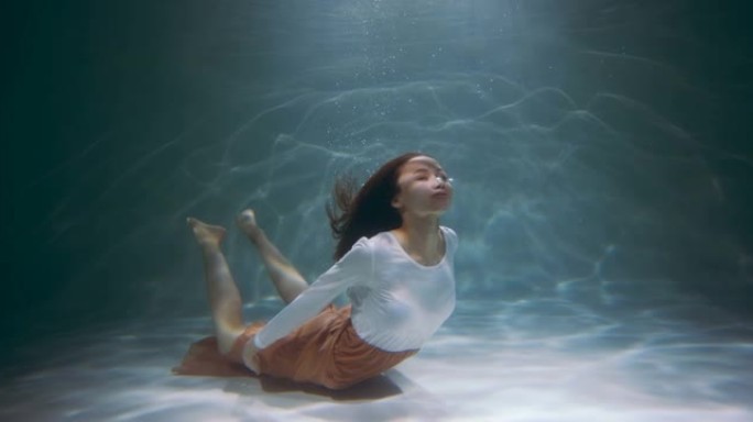 电影般的水下肖像，年轻美丽的多民族女性穿着休闲优雅的衣服潜水，漂浮慢动作。