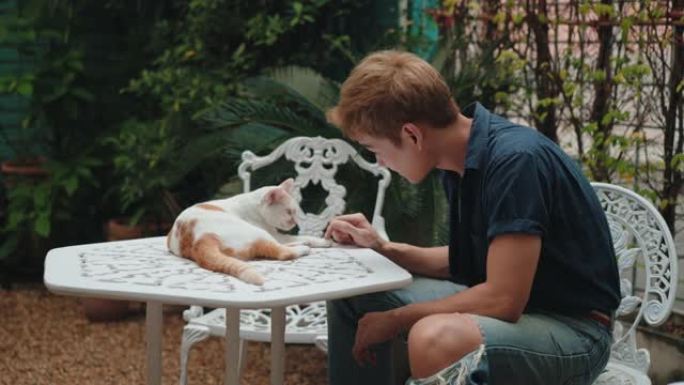 年轻人在院子里和一只猫一起享受