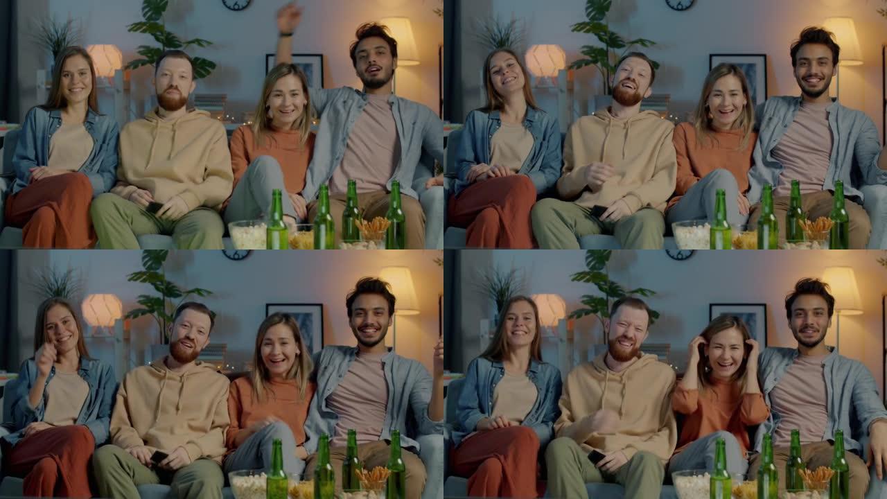 快乐的男人和女人的肖像坐在沙发上看电视指着相机，晚上在家里笑
