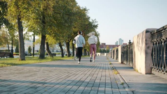 夏日在城市街道户外慢跑的年轻活跃夫妇的后景