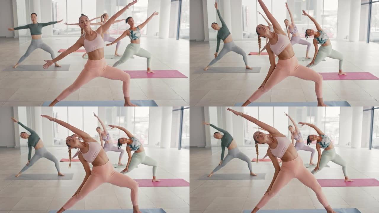 一群健康的女性在瑜伽课上练习战士两个姿势。普拉提教练在健康和保健工作室上课，同时伸展关节以实现身体身