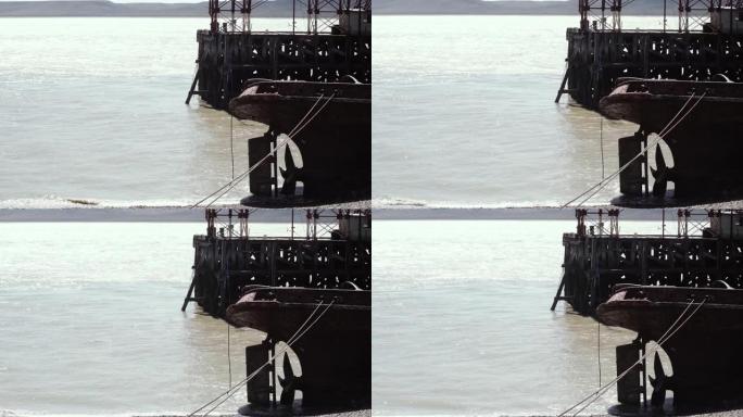 铁锈的船体部分从阿根廷巴塔哥尼亚一艘沉船拖船的水面、船尾、舵和螺旋桨突出。
