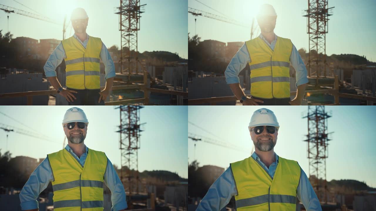 在阳光明媚的晴天，自信的大胡子土木工程师-戴着墨镜的建筑师在建筑工地的相机上微笑。男人戴着安全帽，衬