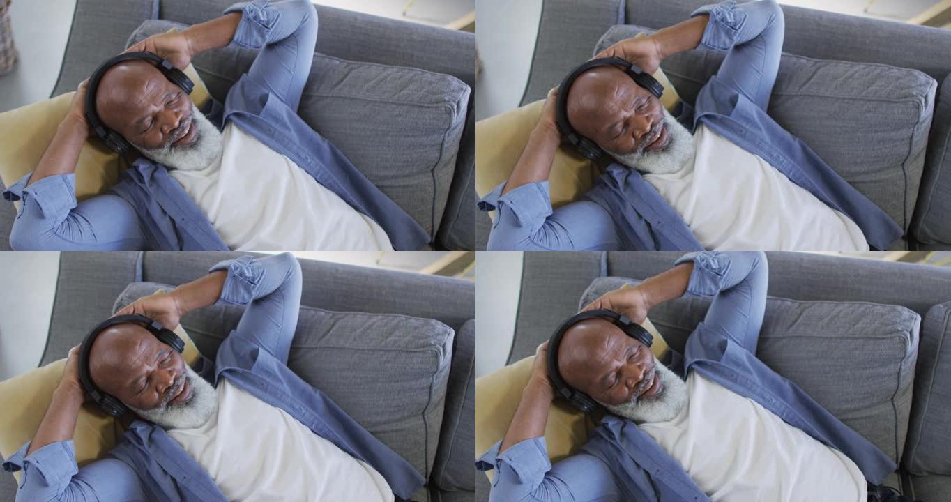 客厅的老年非洲裔男子躺在沙发上，戴着耳机