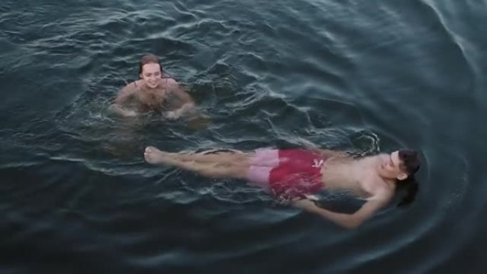 年轻夫妇在湖中游泳的俯视图