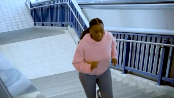 非裔美国妇女在陡峭的混凝土楼梯上奔跑