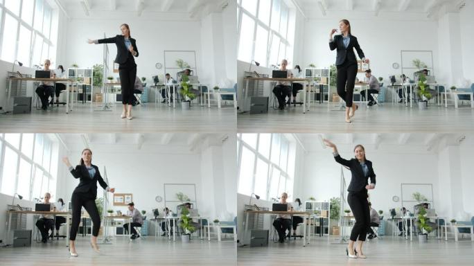 优雅的年轻女子在工作场所跳舞，而员工在办公桌前工作，则转向音乐