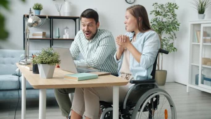 残障妇女使用笔记本电脑与丈夫交谈，然后得到好消息拥抱大笑