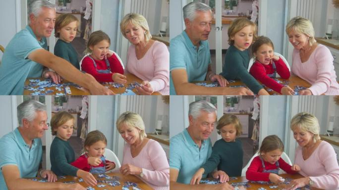 祖父母的孙子孙女坐在家里的桌子旁一起做拼图游戏