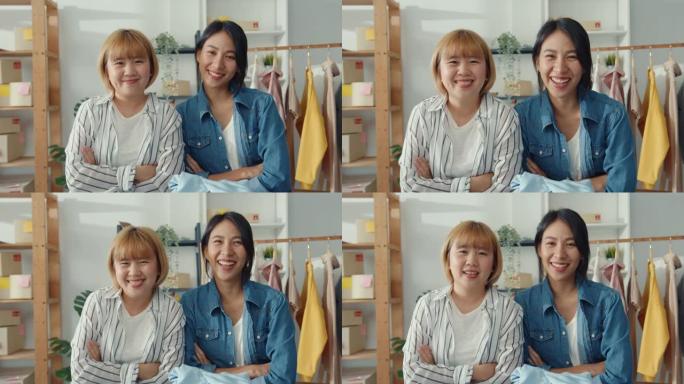 年轻的亚洲女性时装设计师的肖像在家庭办公室的服装店工作时感到幸福的微笑，双臂交叉，看着相机。