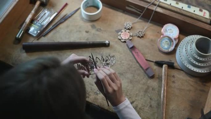 高角度视图正上方亚洲中国女学生用钳子调节手在大学工作台上制作手工饰品