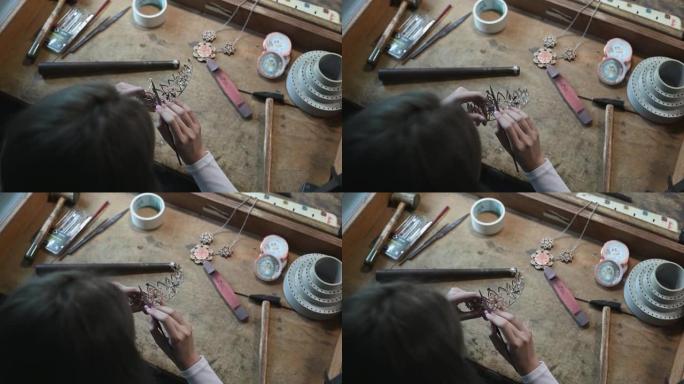 高角度视图正上方亚洲中国女学生用钳子调节手在大学工作台上制作手工饰品