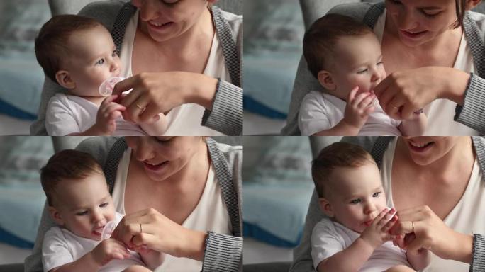 婴儿握着硅胶刷毛，轻轻按摩新的牙齿和牙龈
