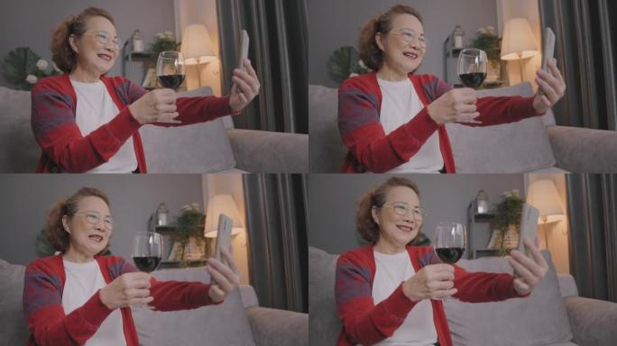 微笑的退休老妇人拿着酒杯敬酒网上约会与男友通过视频通话。
