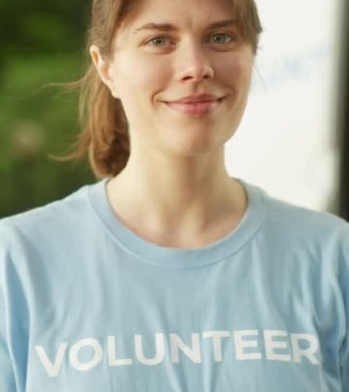 一位快乐乐于助人的年轻女志愿者的垂直肖像。美丽的高加索黑发女人微笑着，看着相机。人道主义援助、捐赠中