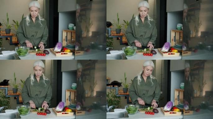 厨房里用刀切黄瓜的成熟女士烹饪蔬菜沙拉肖像