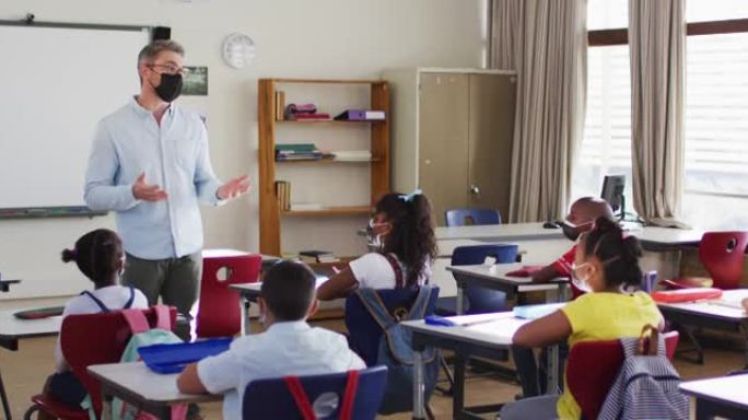 戴口罩的白人男老师在学校里教班上的学生