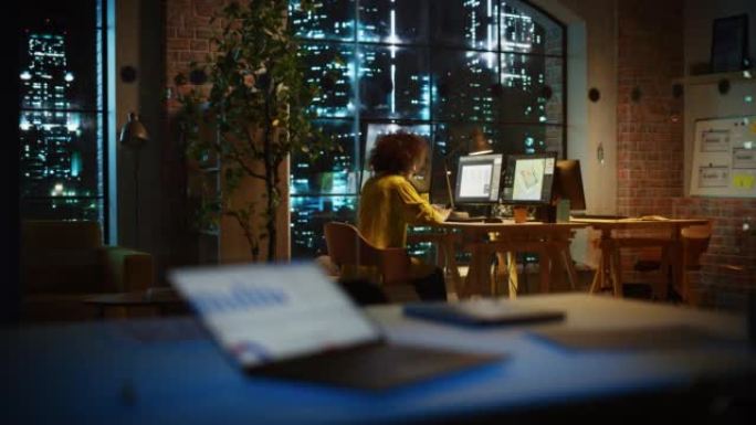 成功的阿拉伯女性晚上独自坐在创意机构，经理致力于为客户实施业务战略。兴奋的专家在计算机上编写公司项目