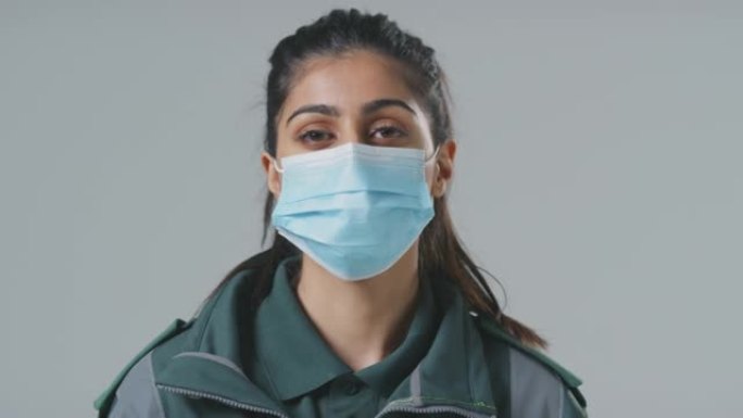 工作室肖像的年轻女性护理人员戴着面具在朴素的背景下