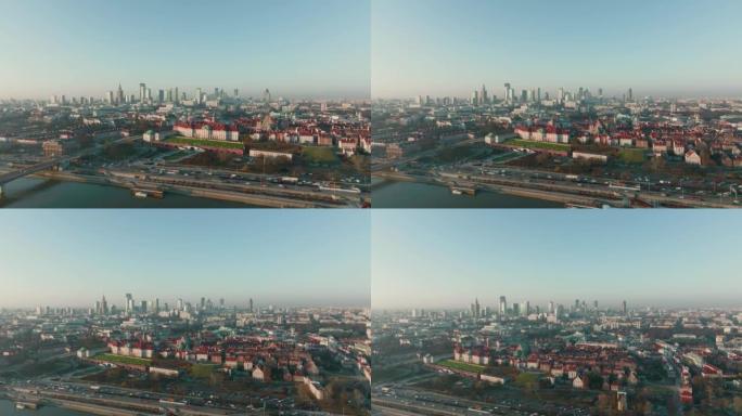 无人机在华沙城市景观天际线上方高高飞行，汽车交通在晴朗的蓝天下沿着维斯拉河移动。