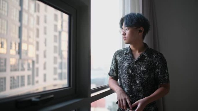 周末使用智能手机靠在客厅窗户上的亚洲中国少年