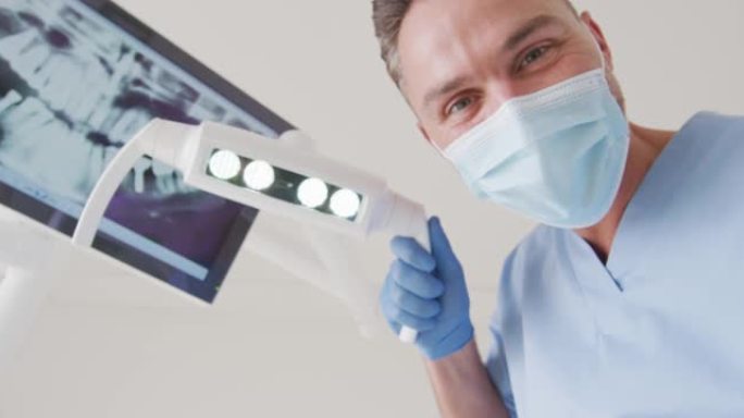 在现代牙科诊所用口罩检查牙齿的高加索男性牙医